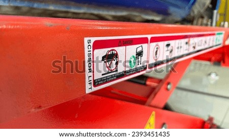 Safety sign sticker on red steel bar, Safety identification on machine in the garage or car service center, Safety in workplace concept 