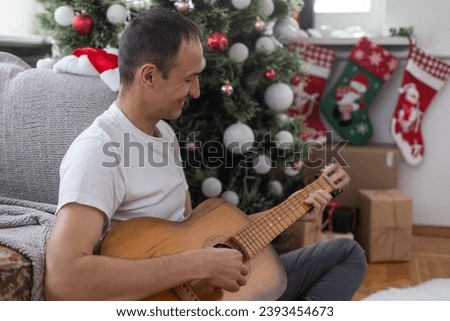 Portrait of young man celebrating party of his birthday at home and playing guitar.
