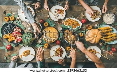A family gathered at the dinner table on Thanksgiving, celebrating the holiday, On the table is a group of dishes, food, sweets, drinks, and turkey Royalty-Free Stock Photo #2393463153