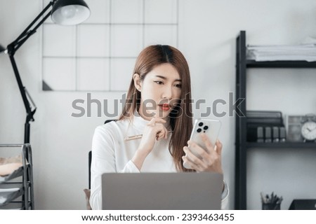 Business woman using smartphone and laptop computer in office. Happy woman, entrepreneur, small business owner working online.