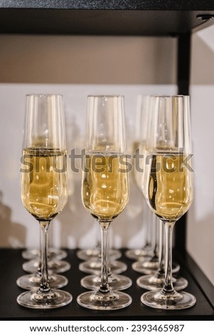 Champagne flutes in holiday. Champagne glasses in restaurant. Glasses are filled with champaign. Celebration of the Happy New Year 2024, Christmas holidays, birthday party, wedding and baptism.