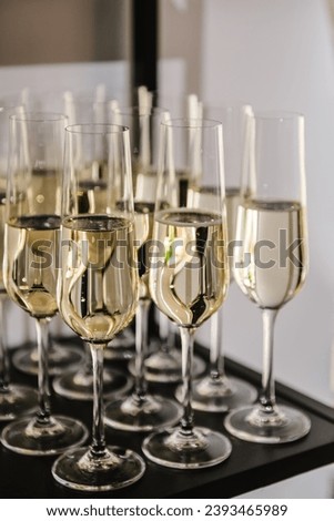 Champagne glasses in restaurant. Champagne flutes in holiday. Glasses are filled with champaign. Celebration of the Happy New Year 2024, Christmas holidays, birthday party, wedding and baptism.