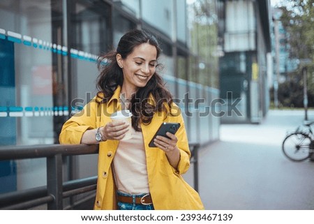 Girl using mobile phone on a city street. Freelance work, communication, business, connection, mobile apps, meeting online, travel concept. Connected city worker.  Royalty-Free Stock Photo #2393467139