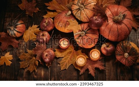 Brown table with autumn leaves and candles, pumpkins, Thanksgiving and holiday atmosphere. Royalty-Free Stock Photo #2393467325