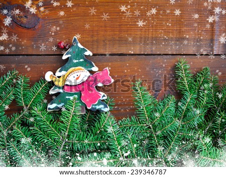 Branches of fir with snowman and Christmas decorations on wooden background