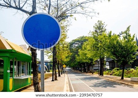 Blank road sign on the side of asphalt road with trees and blue sky background. Blank road sign for copy space