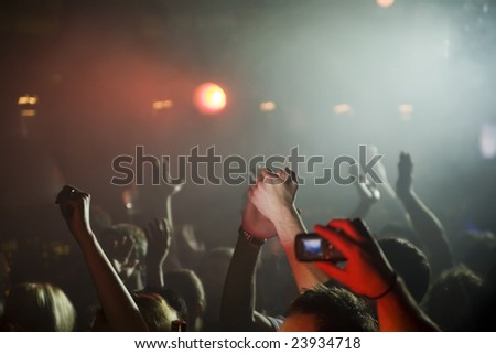 Man takes pictures on his cellphone at concert in night club.