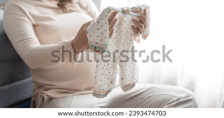 Pregnant asian woman getting ready for the maternity hospital preparing and planning baby clothes for new baby of pregnancy packing for maternity hospital at home  Royalty-Free Stock Photo #2393474703