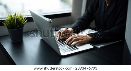 Close up Asian business woman using laptop to calculate tax and financial data of business at office Royalty-Free Stock Photo #2393476793