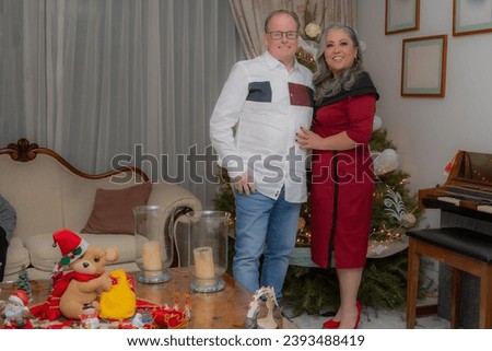 Full length portrait of happy smiling couple dressed elegantly near Christmas tree with blurred background, Christmas scene at home with decoration, formal wear, happy and smiling expression