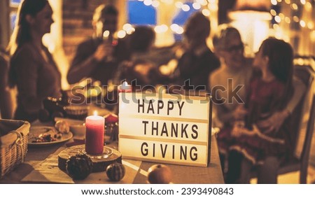 A banner with Happy Thanksgiving, and in the background a family consisting of grandparents and grandchildren laughing and celebrating the holiday. Royalty-Free Stock Photo #2393490843