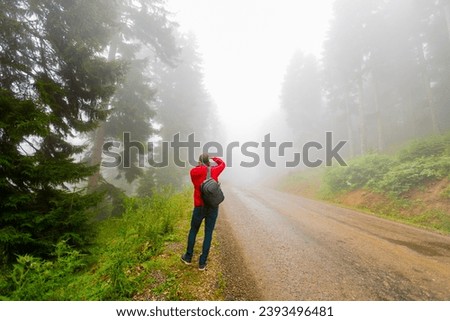 A lonely young man taking pictures on a foggy mountain road, Giresun, Turkey.