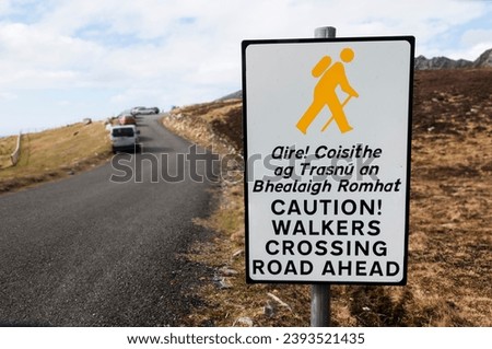 Sign in Irish and English, warning drivers that walkers are crossing the road ahead.