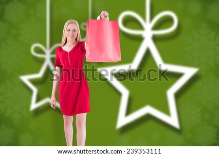Pretty blonde in red dress holding shopping bag against blurred christmas background