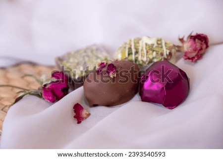 Chocolate Pieces with Elegant Flowers and Roses on Pink and White Background. Romantic Concept with Mock-Up Space for Customization. Ideas for Valentine's Day, Celebrations, and Gourmet Gift Concepts