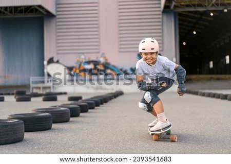 asian child skater or kid girl fun playing skateboard or enjoy riding carving surf skate on car tires track in skatepark lane to smile for extreme sports exercise and wears helmet guard to body safety