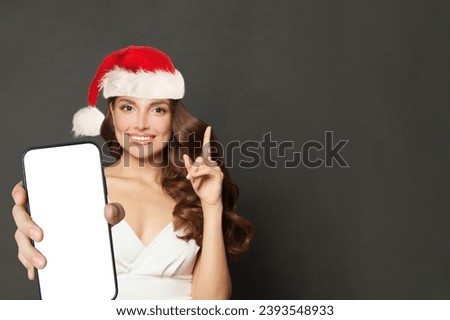 Beautiful woman in Santa hat holding smartphone with blank empty display screen