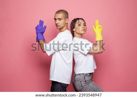 Portrait of successful confident strong young man and woman ready to clean house on pink background