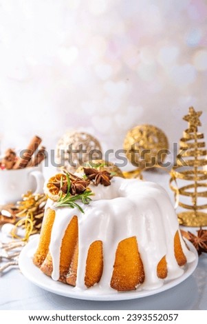 Christmas bundt cake decorated with sugar icing, orange and rosemary. Traditional Christmas and New Year baked dessert, vanilla sponge fruit cake, in white xmas decorated background