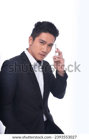 portrait of young businessman in black suit ,shirt, with holding cellphone standing posing white background