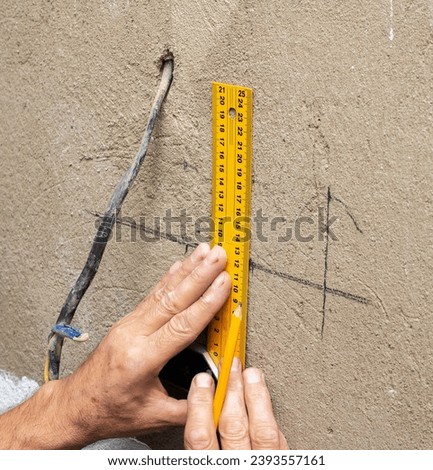 Markings for sockets on the wall, a man is installing sockets in the wall