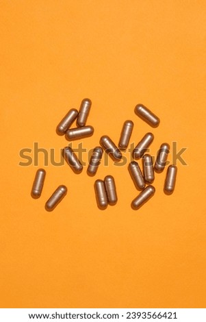 Top view of hard capsules isolated on orange background. Pills in hard capsule form have the ability to absorb water and dissolve quickly in the body.