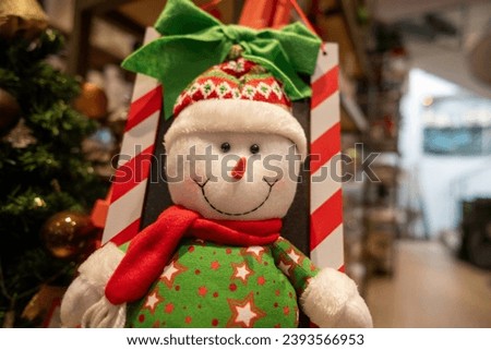 A snowman ornament hanging from a Christmas tree 