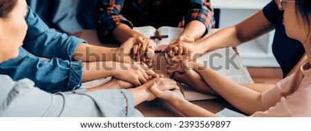 Cropped image of diversity people hand praying together at wooden church on bible book while hold hand together with believe. Concept of hope, religion, faith, god blessing concept. Burgeoning. Royalty-Free Stock Photo #2393569897