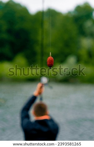 Fisherman casts a fishing rod or spinning rod into the water while sitting on the river bank on the pier Pull fish out of the lake sport fishing Royalty-Free Stock Photo #2393581265