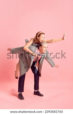 Young man and woman, employees, colleagues having fun and laughing against pink studio background. Concept of emotions, business, profession and occupation, lifestyle, friendship