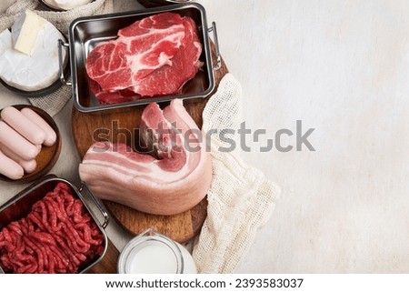 Saturated fats on tables. Raw meat, sausages, cheese, butter. Bad food concept. Top view, copy space. Royalty-Free Stock Photo #2393583037