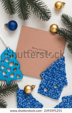 Christmas composition with crochet blue Christmas houses and greeting card.