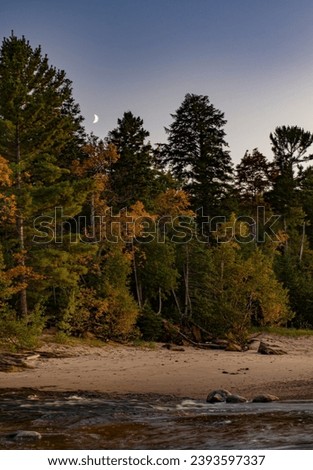 The moon rises over the forest at the Lake Superior shore at Hurricane River beach in Pictured Rocks National Lakeshore, Alger County, Michigan