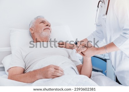 Asian female doctor holding hands and supporting sad senior man lying in hospital bed. Support first aid concept. Psychological assistance Royalty-Free Stock Photo #2393602381