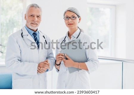 Portrait of man and woman doctors standing in hospital hallway. Medical workers, caregivers, nurses teamwork. Healthcare concept. General practitioners, family doctors Royalty-Free Stock Photo #2393603417