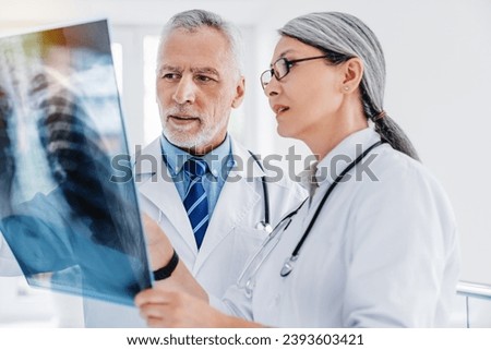 Two doctors examines X-ray scan in clinic. Bones and rib cage, lungs image in hospital. Respiratory diseases, coronavirus treatment. Pneumonia Royalty-Free Stock Photo #2393603421