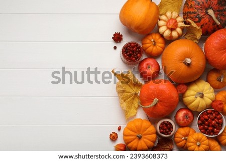 Flat lay composition with autumn leaves, berries and pumpkins on white wooden table, space for text