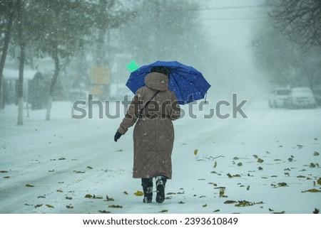 The picture of the grandmother holding a purple umbrella because outside there is a yellow wind and big flakes in the winter