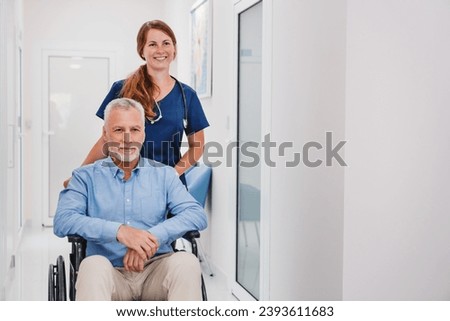 Young female nurse doctor pushes senior man in wheelchair in hospital hallway. Caregiver medical worker taking care of disabled immobile senior man