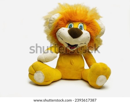   A toy lion cub, with yellow hair, who smiles, on a white isolated background. For cards, gifts, for fabric.                              Royalty-Free Stock Photo #2393617387