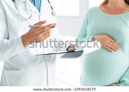 Cropped image of pregnant woman visiting doctor. Gynecologist midwife prescribing medications pills treatment to expectant mother. Gestation, lactation, fetus health Royalty-Free Stock Photo #2393618579