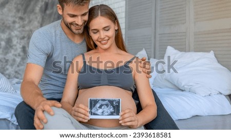 Beautiful pregnant woman and her handsome husband looking a baby ultrasound scan photos. Future happy parents expecting a baby with x-ray image photo. Royalty-Free Stock Photo #2393618581