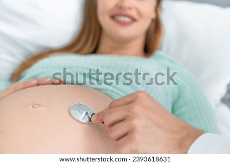 Young pregnant woman expecting a baby doctor visit. Gynecologist midwife listening to fetus embryo heartbeat with stethoscope. Maternity treatment Royalty-Free Stock Photo #2393618631