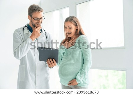 Male doctor showing prescription document to pregnant woman in clinic. Positive news to expectant mother. Healthy fetus, maternity concept. Prescription of medications Royalty-Free Stock Photo #2393618673