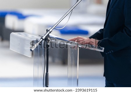 A male speaker captivates the audience with a powerful speech, creating an impactful moment Royalty-Free Stock Photo #2393619115