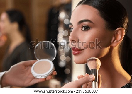 Makeup artist working with beautiful woman in dressing room, closeup