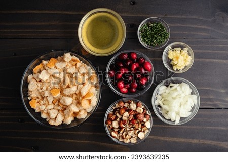 Cranberry Hazelnut Stuffing Ingredients in Prep Bowls: Breadcrumbs, cranberries, and other dressing ingredients on a dark wooden table Royalty-Free Stock Photo #2393639235