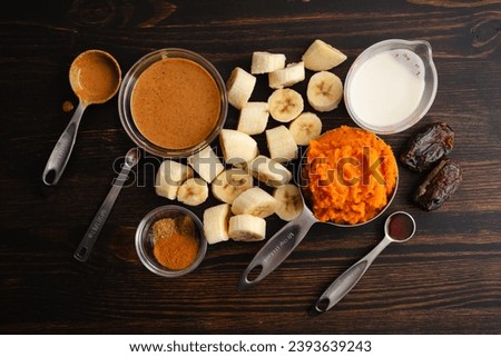 Pumpkin Pie Smoothie Bowl Measured Ingredients: Frozen banana  pumpkin puree, oat milk, and other smoothie ingredients in measuring cups and spoons