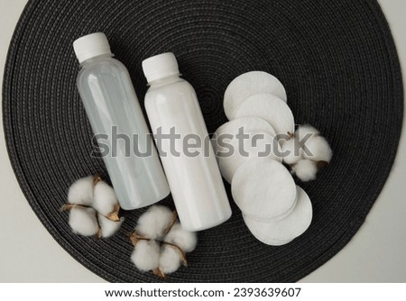 Cosmetic products, cotton pads with cotton flowers on grey background.White cosmetic bottle mockup. Skin care concept.