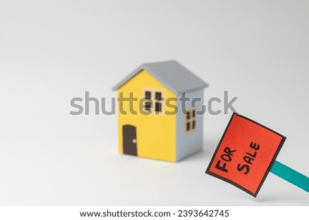 For Sale sign board in front of a  blue and yellow model home, isolated on white background
